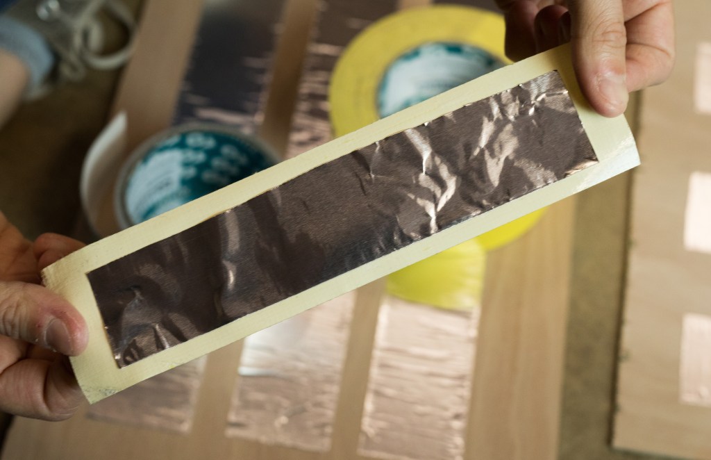 Use a combination of a piece of duct tape and a piece of foil tape folded in half width-ways, to create a conductive connection between your foil strips. Cut thin strips of packaging foam to create a foam border around the edge of your larger top plywood pieces. Glue these in place using a suitable multipurpose adhesive, double sided tape (or use adhesive backed foam if you have some). Measure and cut lengths of twin core cable so that each of your plywood pressure pads can be wired back to wherever you intend to locate your Sound Board, speaker and battery pack. It pays to leave an extra 50cm or so of cable, just in case. Each of these cables will probably be a different length depending on the location of the specific step on your stairs. You may also find it useful to number each step to avoid later confusion. Separate the two cable cores at one end of each cut wire length and strip a long bare end on each. Use more foil tape to attach one bare cable to the foil contact on the large top plywood piece for each pressure pad and one on each of the smaller bottom plywood pieces. Depending on the foil tape you use and the equipment available, you might also decide to solder your cable to the foil tape to create a more effective connection. Always make sure you solder in a well ventilated area or outdoors.